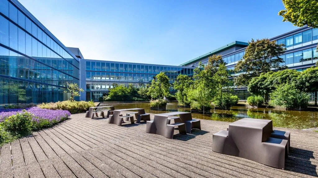 Moderne buitenruimte met zitplekken, vijver en begroeiing bij Kessler Park kantoorgebouw.